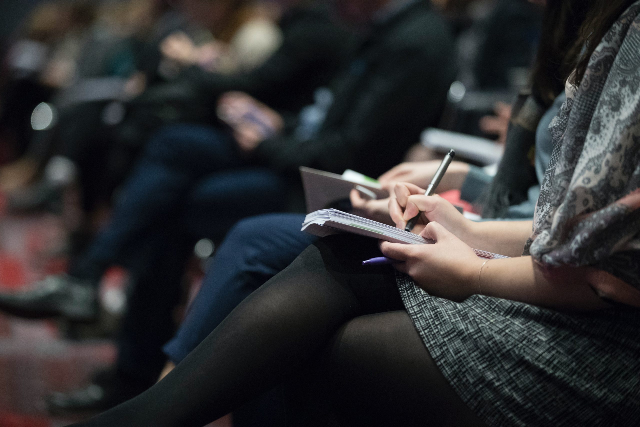 seated people taking notes at a press conference